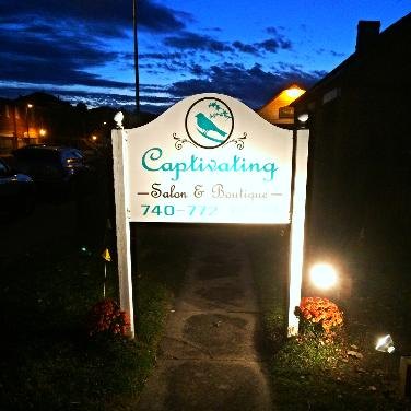 An illuminated monument sign glowing at dusk outside a salon and boutique, installed by Bright Solutions