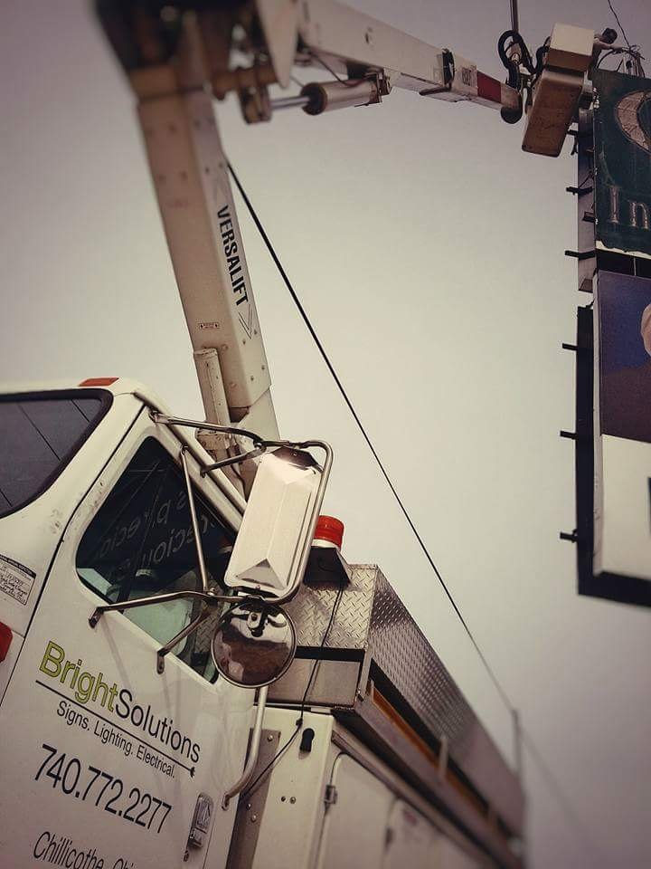 The door of the Bright Solutions bucket truck, reading Signs Lighting Electrical with the Chillicothe phone number